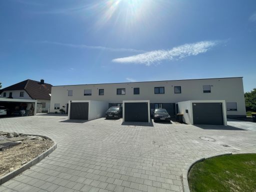 Moderner Wohnkomplex mit Garagen und Stellplätzen bei sonnigem Wetter.