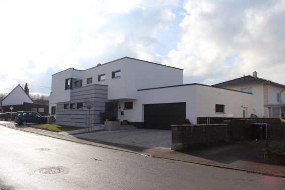 Modernes zweigeschossiges Wohnhaus mit Putzfassade und Garage.