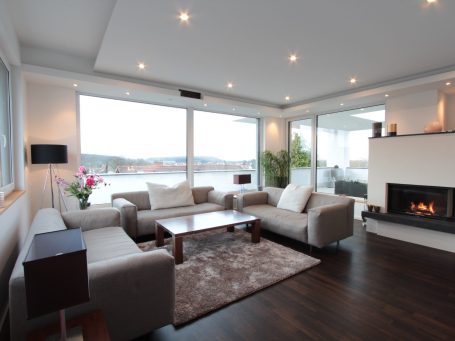 Heller Wohnraum mit gemütlicher Sitzecke, großem Fenster und Blick auf Wasser.