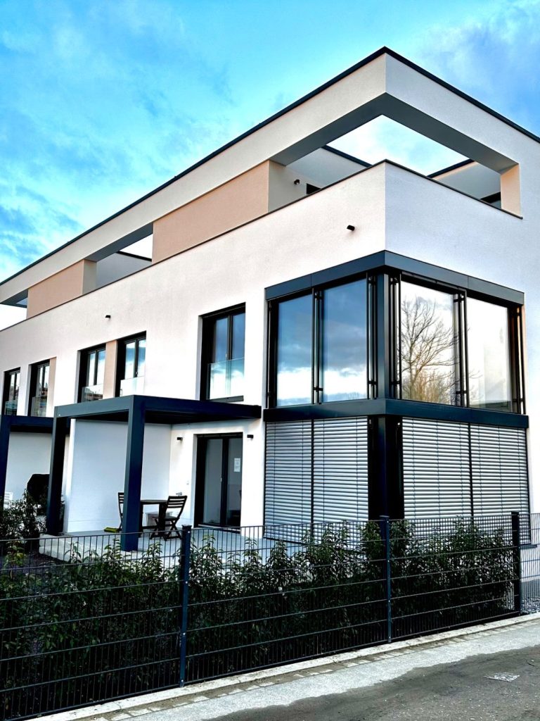 Modernes, mehrstöckiges Gebäude mit großen Fenstern und einem Balkon.