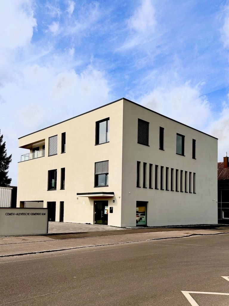Modern, dreistöckiges Gebäude mit Besenputz und großen Fenstern, an einer Straße.