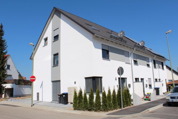 Helles, modernes Wohngebäude mit weißen Wänden und Begrünung.