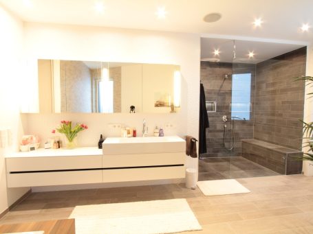 Helles modernes Badezimmer mit Waschtisch, Spiegel und einem Duschbereich.