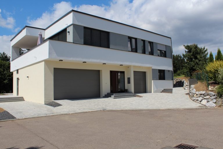 Moderne zweistöckige Villa mit Garagen und gepflastertem Vorbereich.